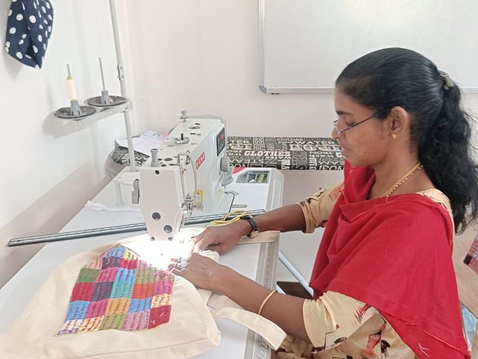 A maker at a sewing machine with a cloth bag and a panel of coloured squares in front of them.