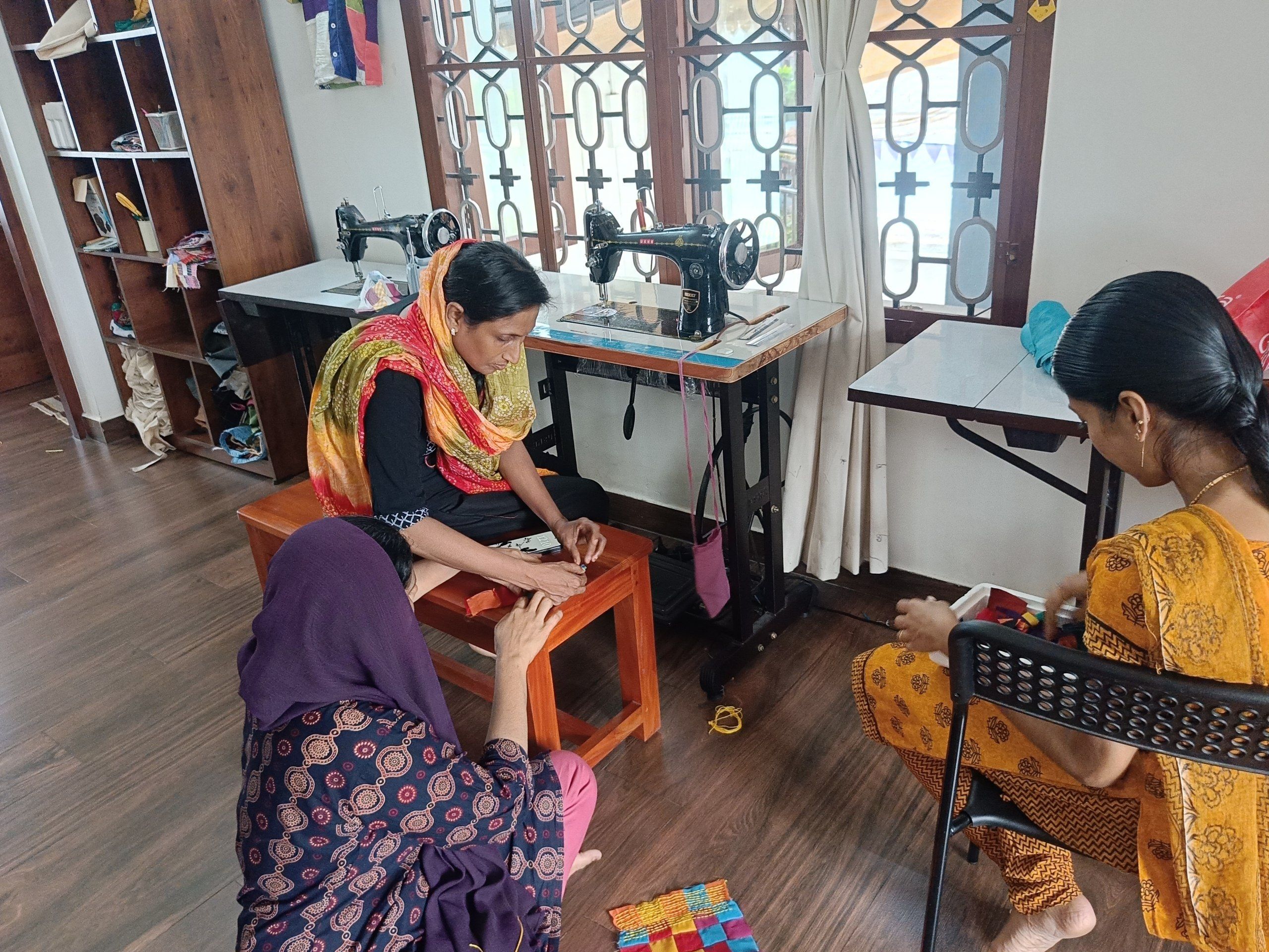 Makers sit working with cloth in a workshop with sewing machines.