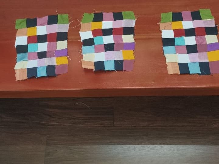 Small panels of coloured squares laid out on a wooden ledge.
