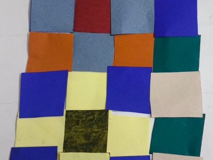 Squares of plain and printed cloth in blue, orange, yellow and green, overlapping in rows on a white background.
