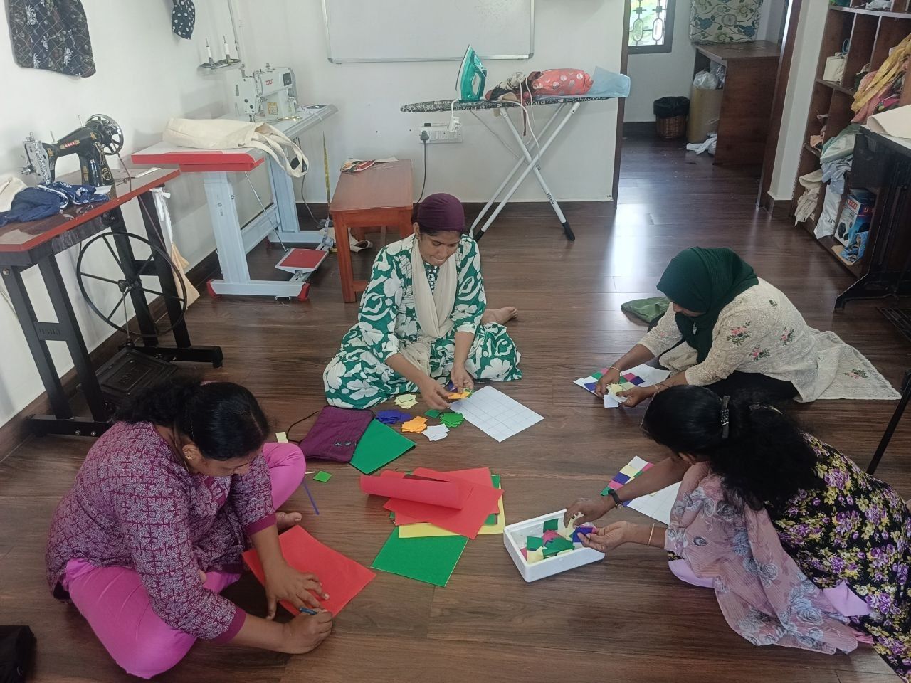On a workshop floor, makers lay coloured squares on sheets of paper.