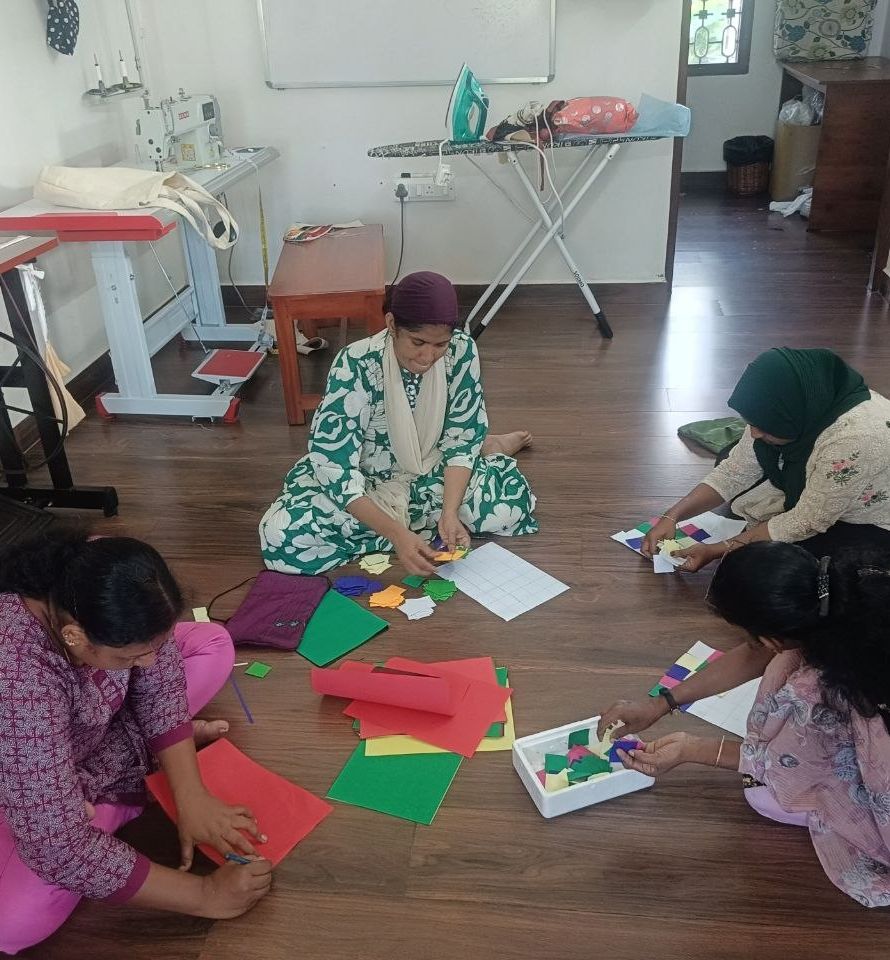 On a workshop floor, makers lay coloured squares on sheets of paper.