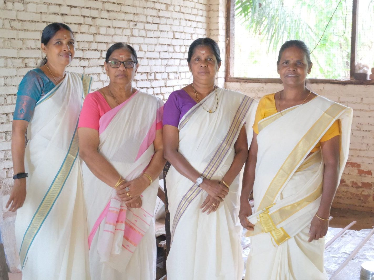 Four weavers of Chengamanad standing together in their Kasavu sarees.